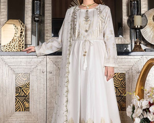 Woman wearing a white embroidered dress in an elegant interior setting.