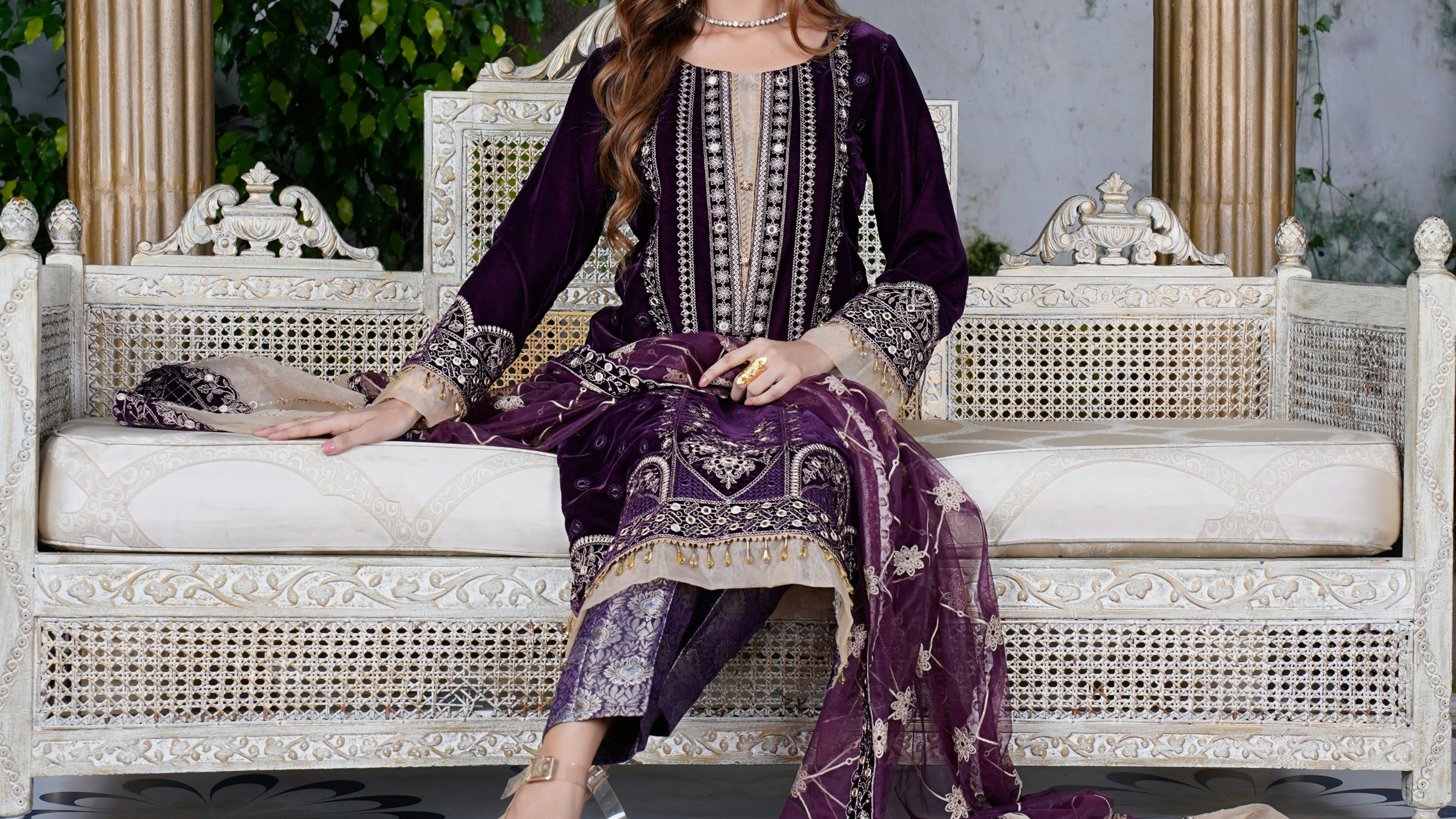Woman in traditional attire sitting on a decorative white chair with a garden background